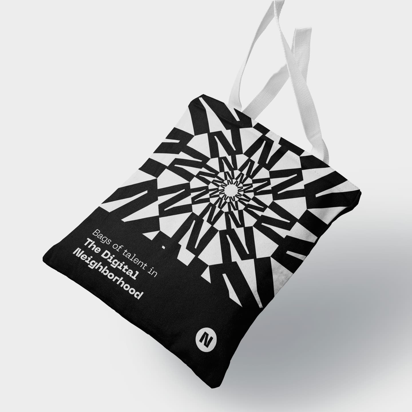 Black and white tote bag with abstract geometric design and the text Bags of talent in The Digital Neighbourhood printed on the front.