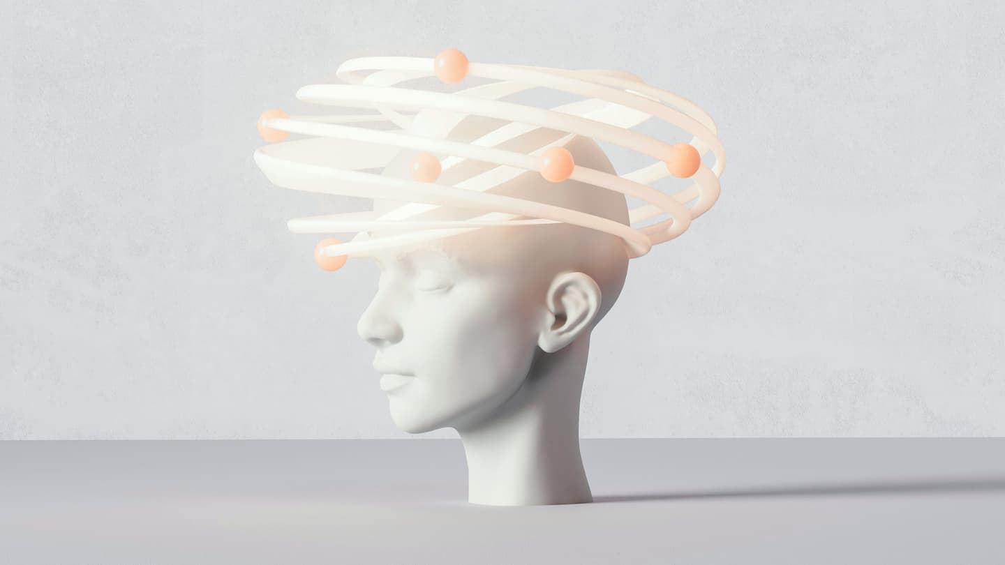 A white mannequin head with eyes closed is topped by glowing, spiral rings with orange spheres, resembling an abstract halo or orbit.