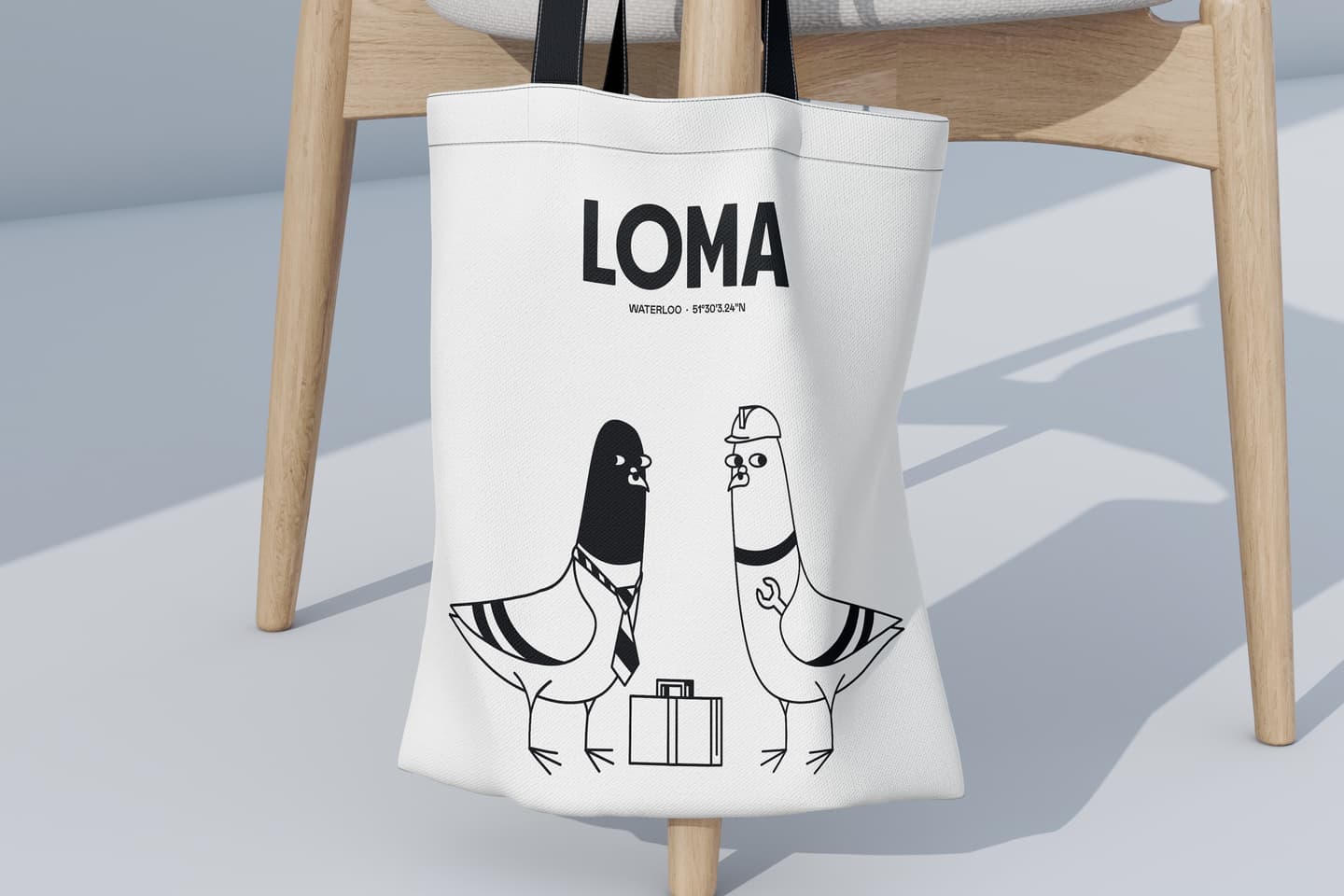 White tote bag with black handles featuring a drawing of two pigeons, one wearing a tie and the other a hat, with a suitcase between them. Text reads LOMA WATERLOO-BISTRO.BAR.